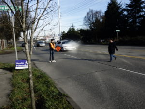 person crossing 5 lanes of traffic with a flagger at Duwamish Longhouse