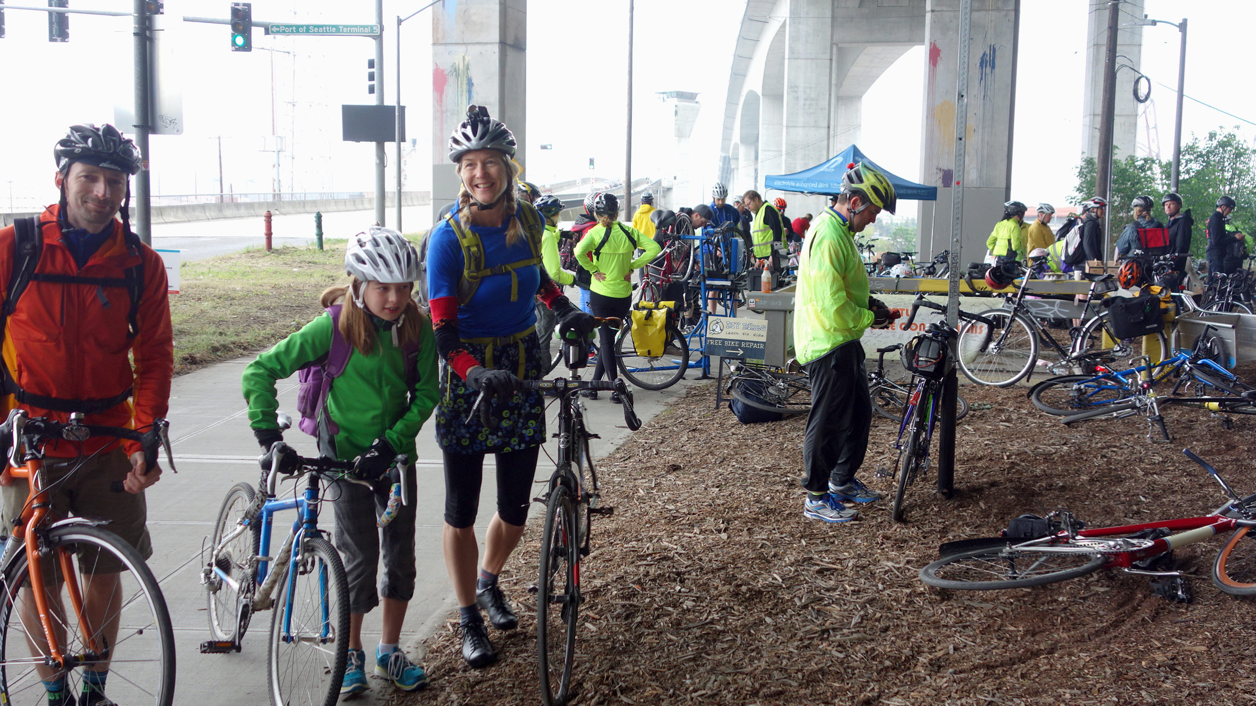 People with bikes, includng kids, gathered at our Bike Everywhere Day Celebration Station. West Seattle bridge in background.